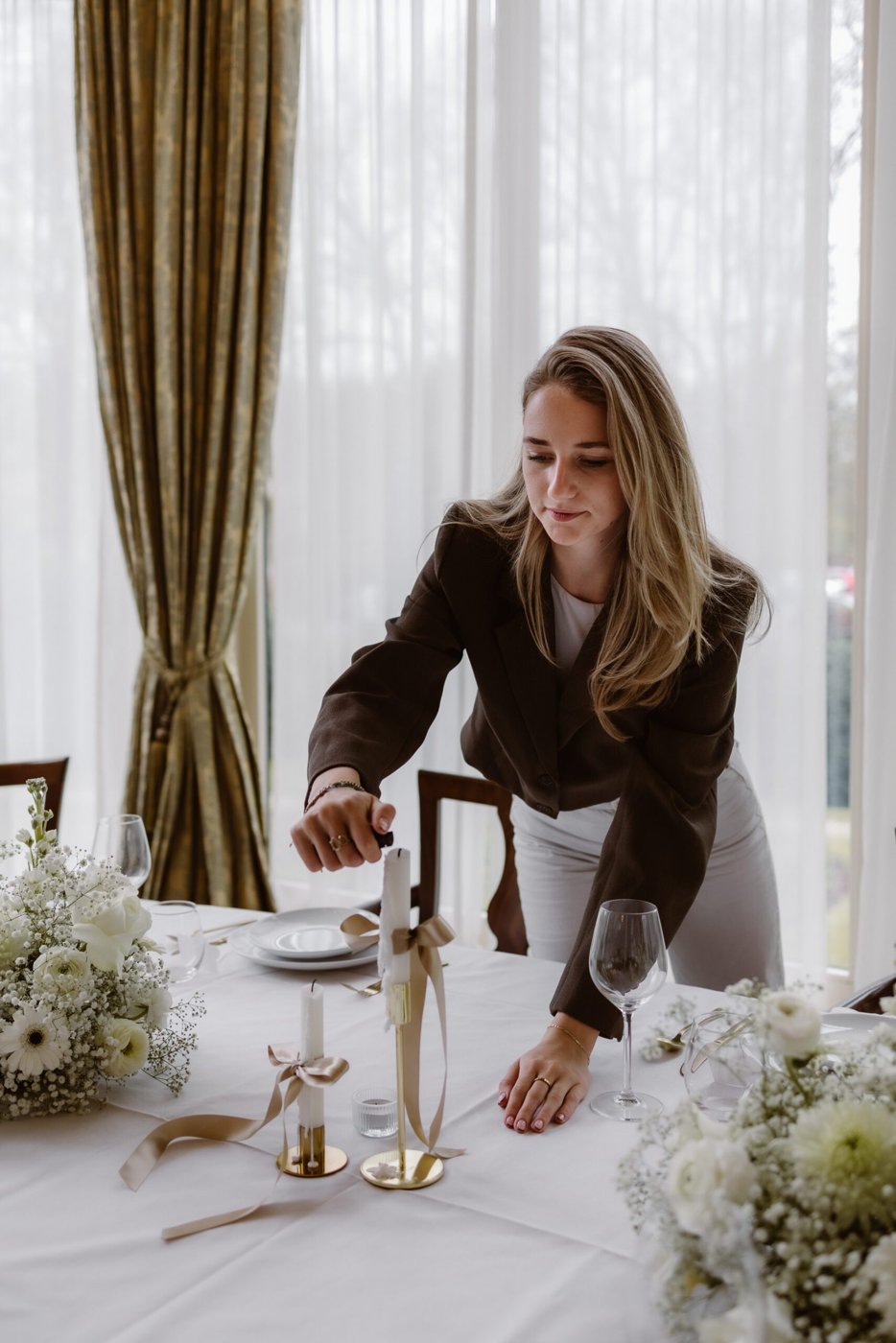 Loes van Leeuwen steekt kaarsen aan op een gestylde bruiloftstafel
